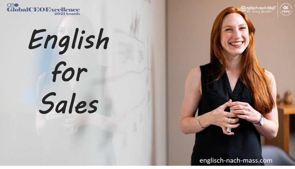 Junge Frau mit langen, braunen Haaren, die an einem Whiteboard steht und lacht. Text: English for Sales englisch-nach-mass.com