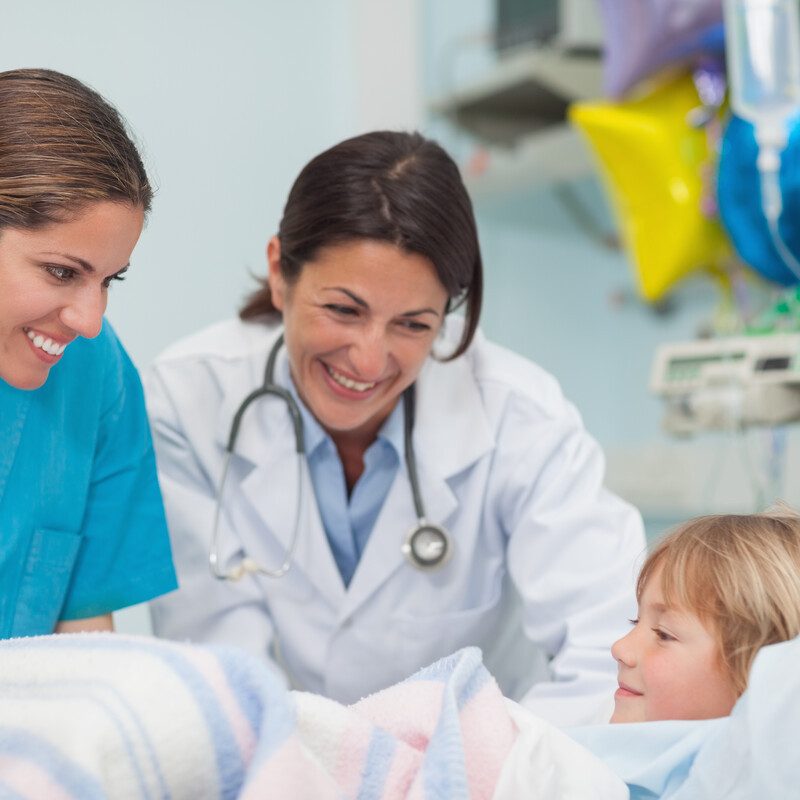 Ärztin und Krankenpflegerin im Krankenhaus am Krankenbett eines kleinen Kindes.